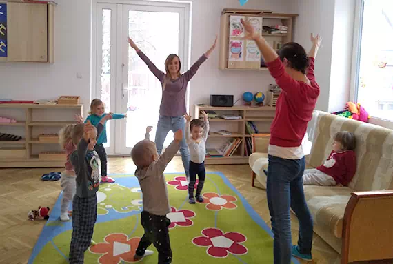 Ciocia z grupą dzieci podczas zabawy ruchowej w sali żłobka